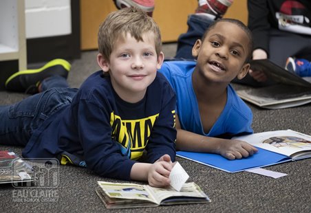 An image of two children in school reading books together.